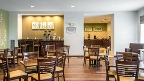 Un hall de hotel con sillas y mesas de madera, una recepción y obras de arte en las paredes.