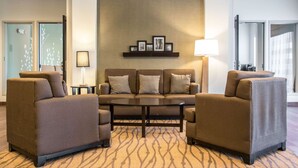 Un moderno vestíbulo de hotel con un conjunto de sofás, una mesa de centro y un estante para cuadros en la pared.
