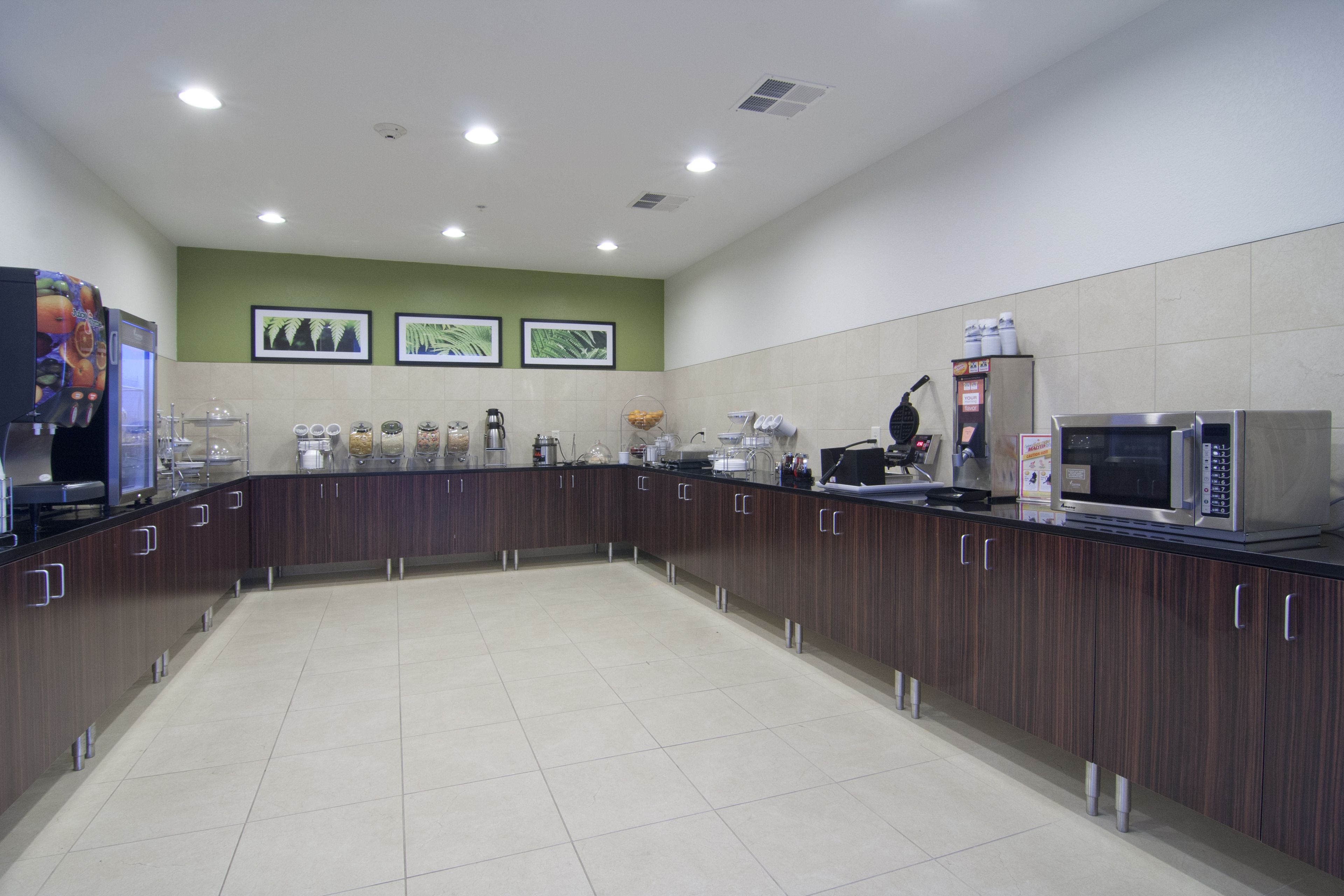 A modern kitchen with a central island, built-in appliances, and a green accent wall.