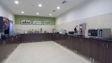A modern kitchen with a central island, built-in appliances, and a green accent wall.