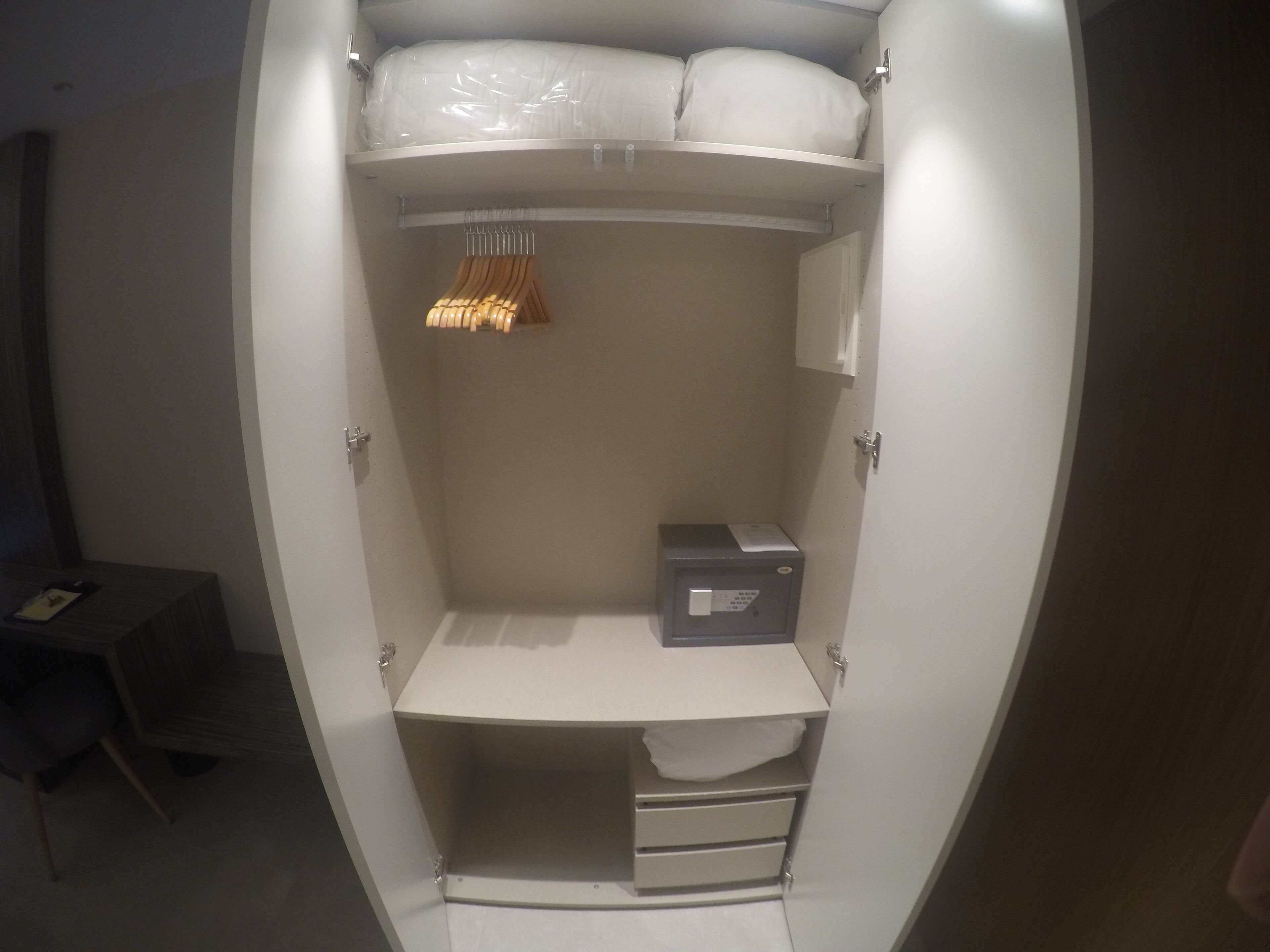 Un dressing avec une tringle à vêtements, une boîte de rangement et une étagère.