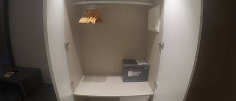 Un vestidor con una barra para colgar, una caja de almacenamiento y un estante.