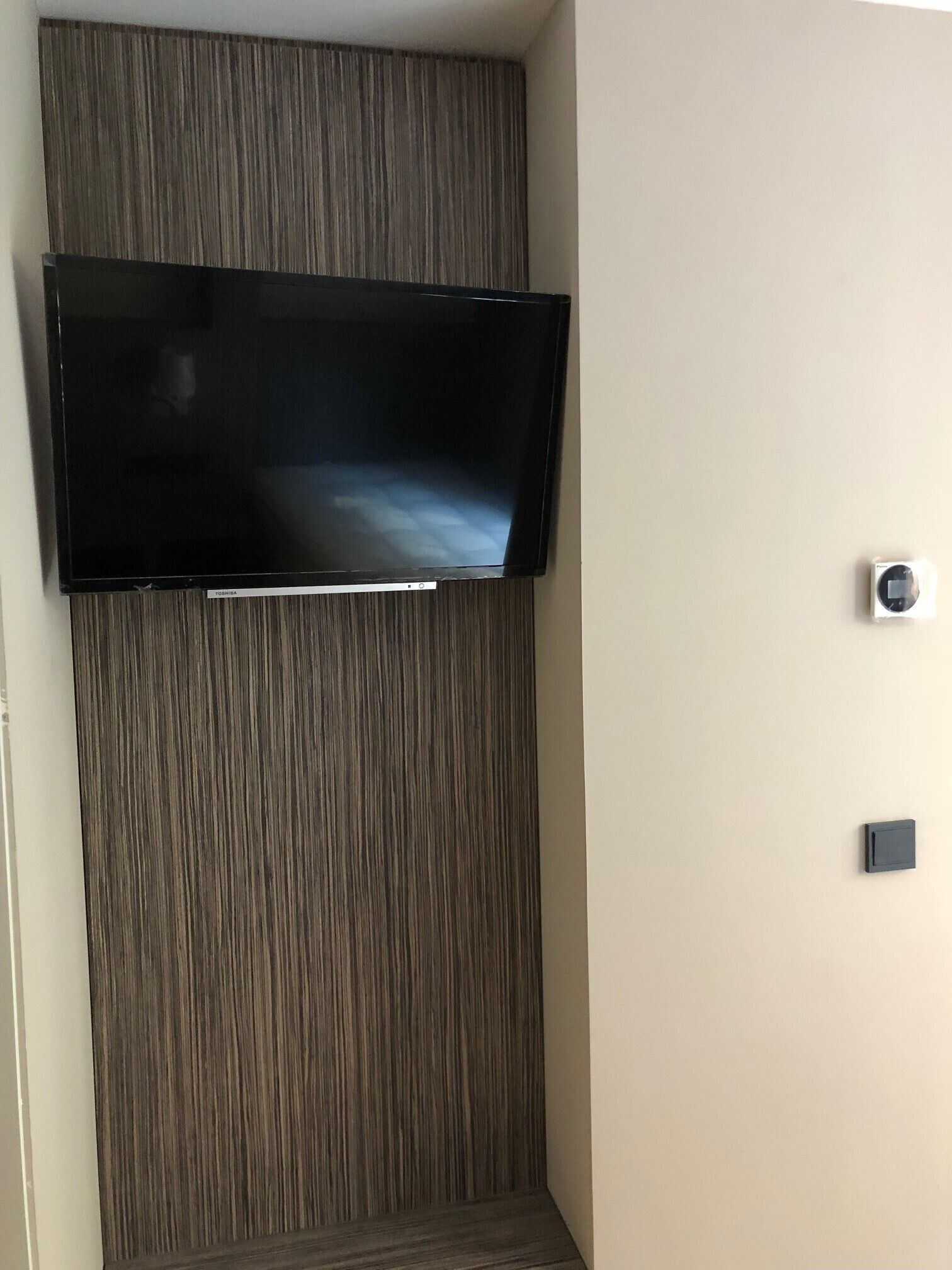 Televisor de pantalla plana montado en una pared de paneles de madera.