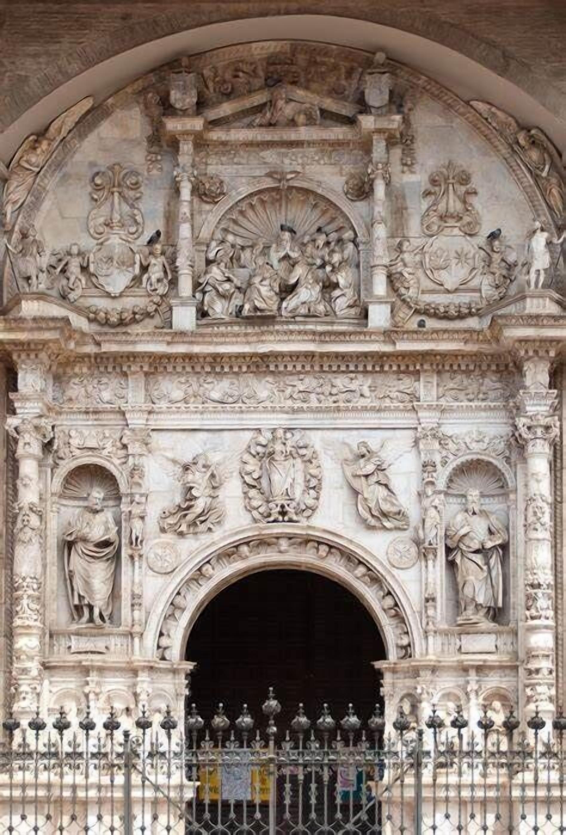 Fachada de piedra ornamentada con intrincados relieves y un amplio arco de entrada.