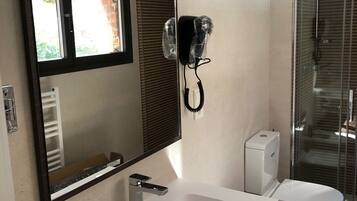 A modern bathroom with a large mirror, a white sink, a toilet, and a shower area.