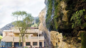 Un hotel amb piscina, una cascada i un paisatge de muntanya al fons.