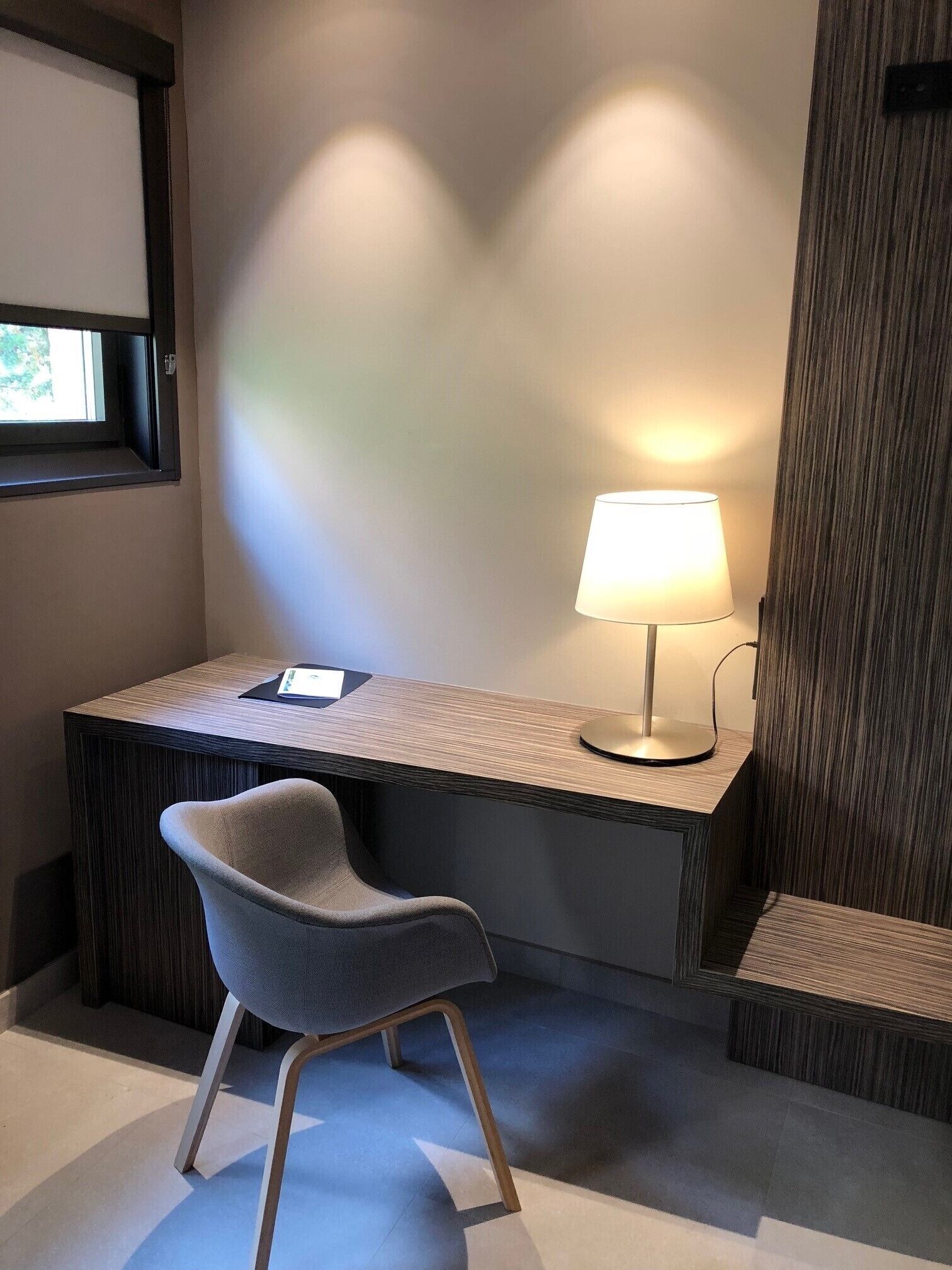 A modern office space with a desk, chair, and a lamp.