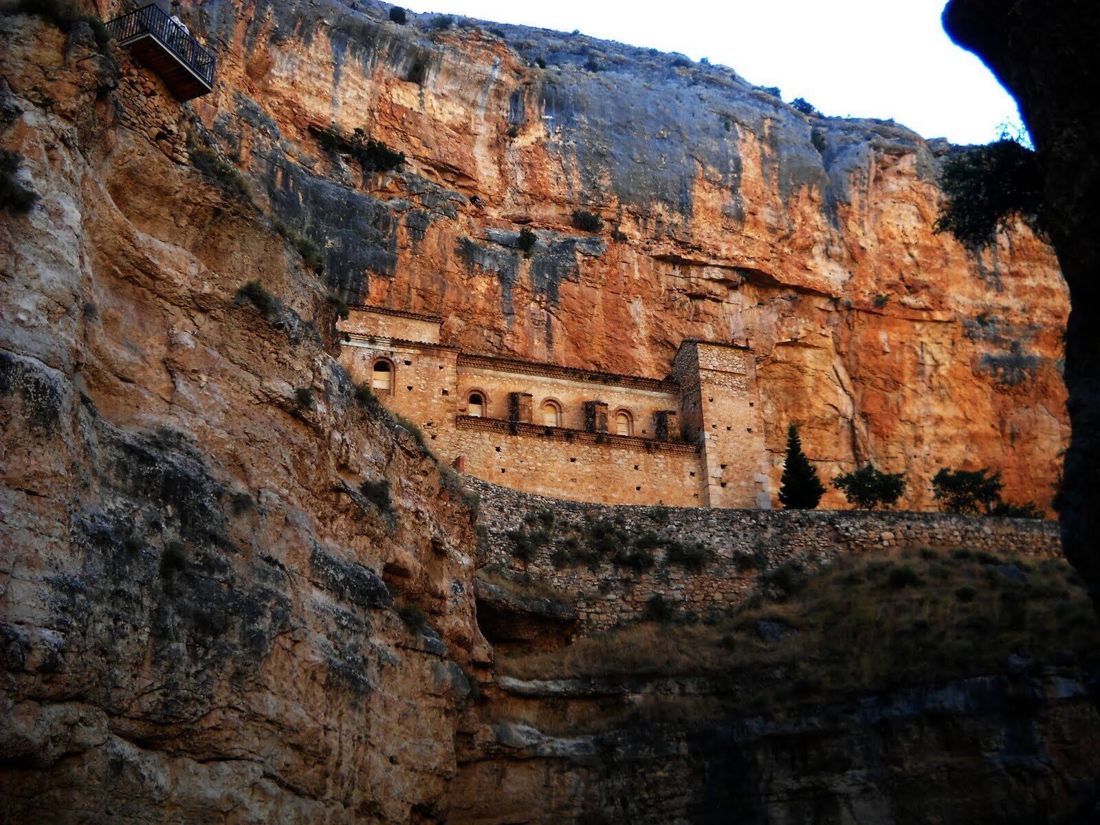 A cliffside building with a series of windows and a balcony.