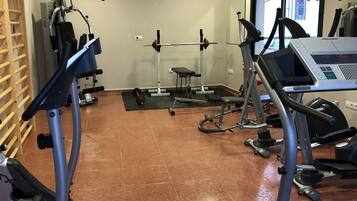 Un gimnasio con cintas de correr, elípticas y equipamiento para levantamiento de pesas.