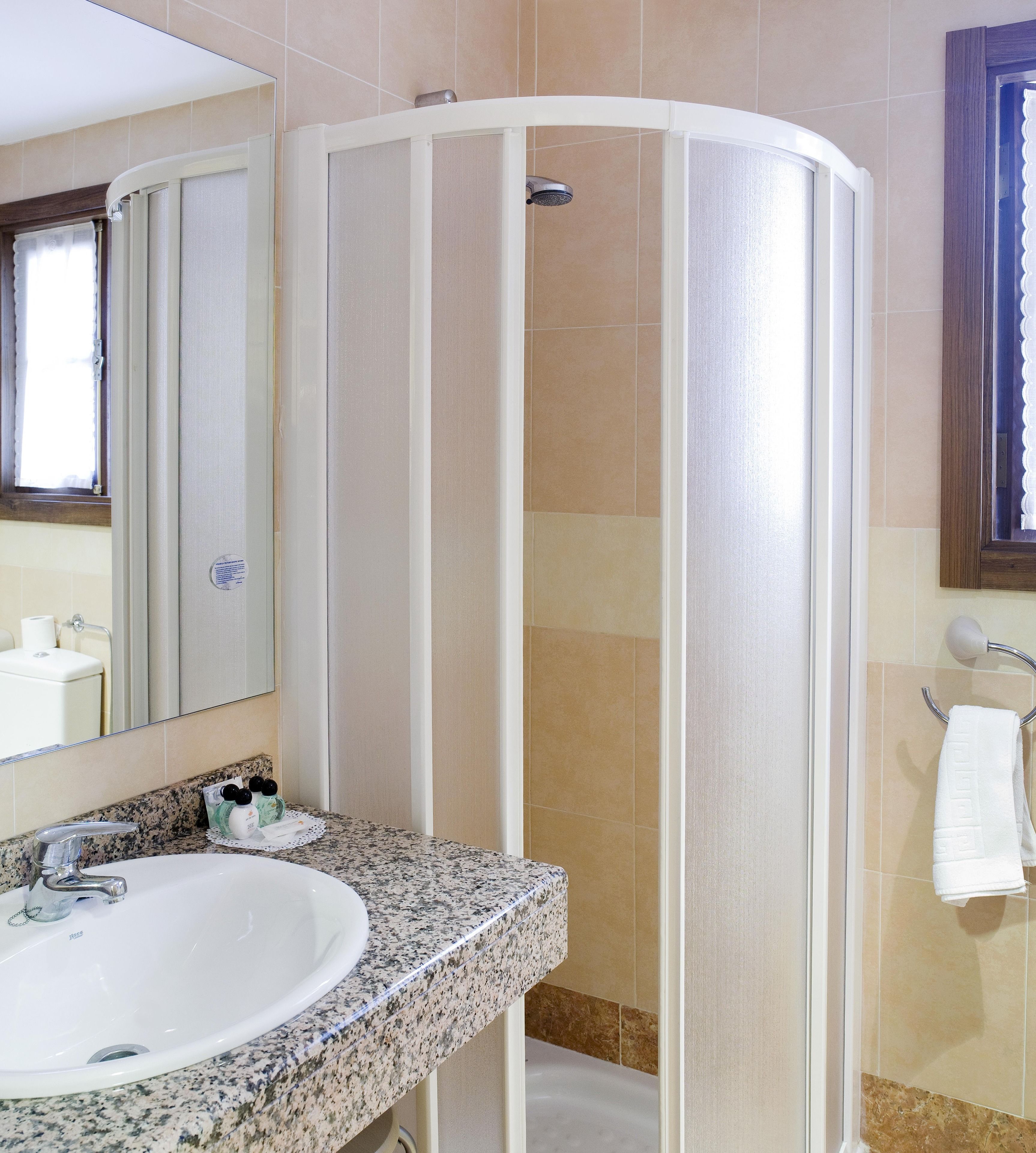 Un baño con lavamanos blanco, cabina de ducha y un perchero para toallas.