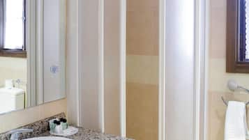 A bathroom with a white sink, a shower enclosure, and a towel rack.