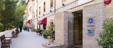 Un hotel con zona de recepción, mobiliario exterior y plantas en macetas.