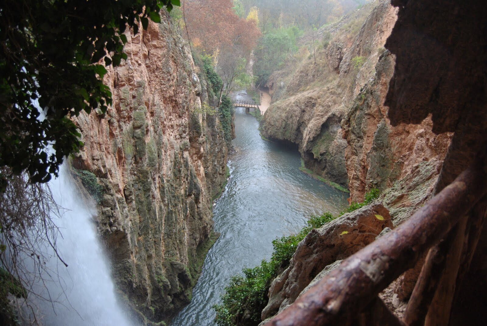 A narrow canyon with a river flowing through it, surrounded by rocky cliffs and vegetation.