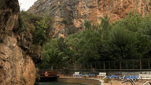 Una piscina d'aigua cristal·lina, envoltada de penya-segada i vegetació.