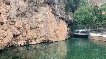 A rocky cliff with a clear pool of water in front of it.