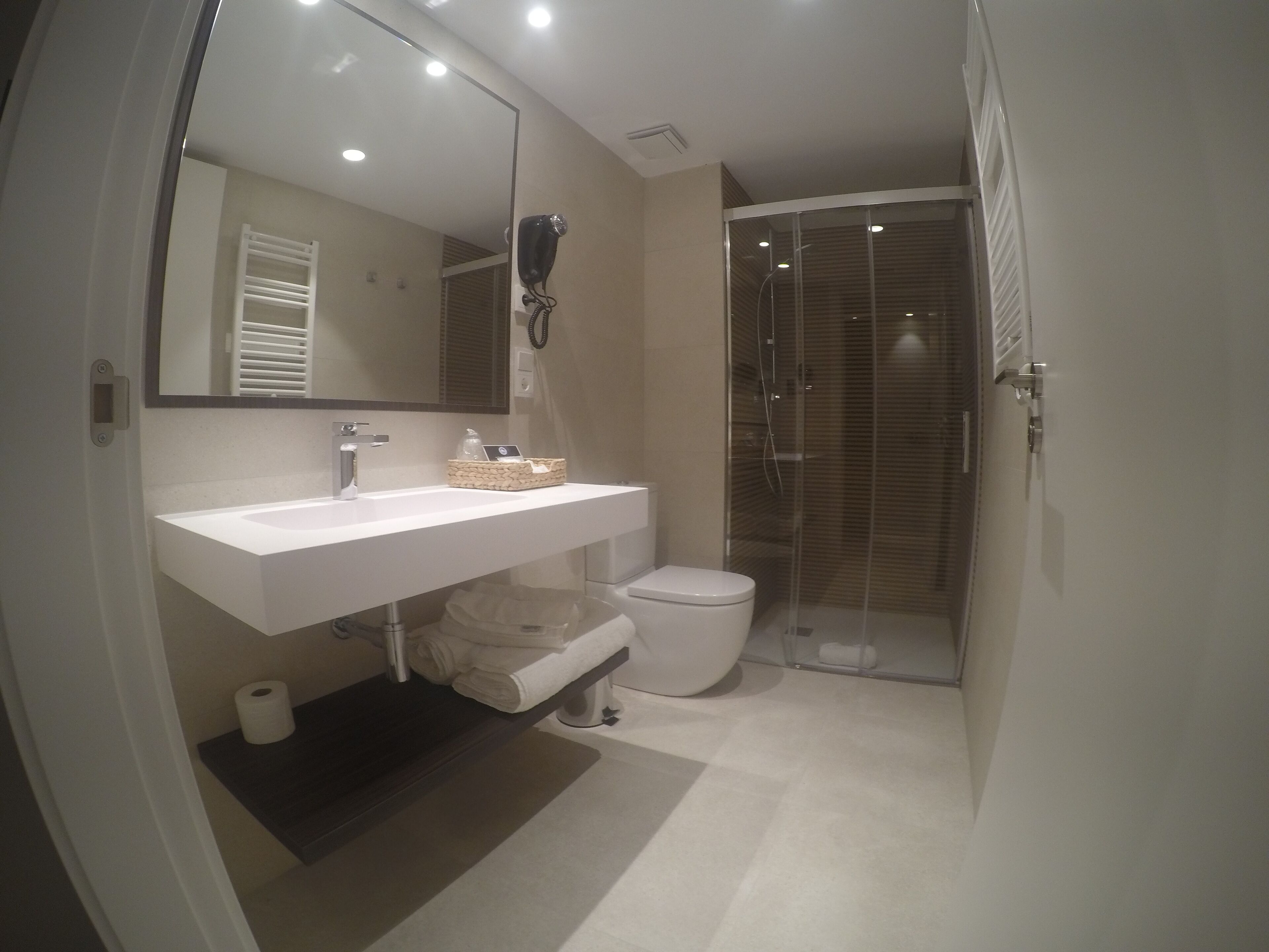 A modern bathroom with a white sink, mirror, and toilet.