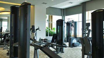 A gym with various exercise equipment, large windows, and a carpeted floor.