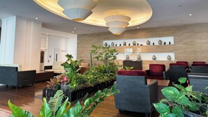 A modern lobby with tiered lighting fixtures, a reception desk, and various plants. - (Bangkok)