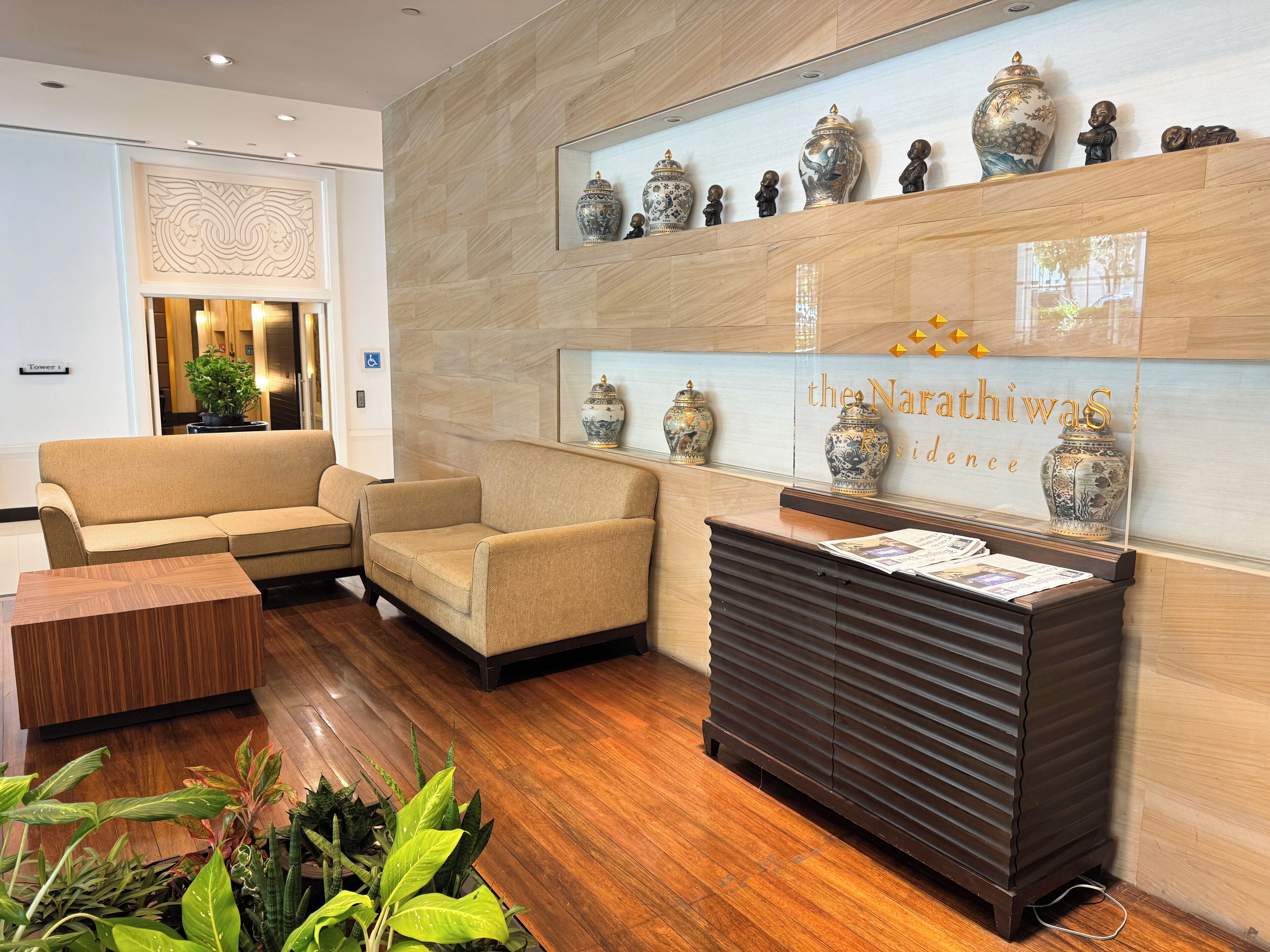 A reception area with a wooden reception desk, beige sofas, and a wall with decorative vases.