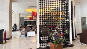 A modern restaurant interior with a black grid partition, a menu stand, and a potted plant. - (Bangkok)