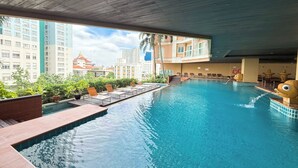 An indoor swimming pool with a view of tall buildings and a traditional pagoda. - The Narathiwas Hotel & Residence Sathorn Bangkok (Bangkok)