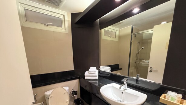 A modern bathroom with a toilet, sink, and mirror. - The Narathiwas Hotel & Residence Sathorn Bangkok (Bangkok)