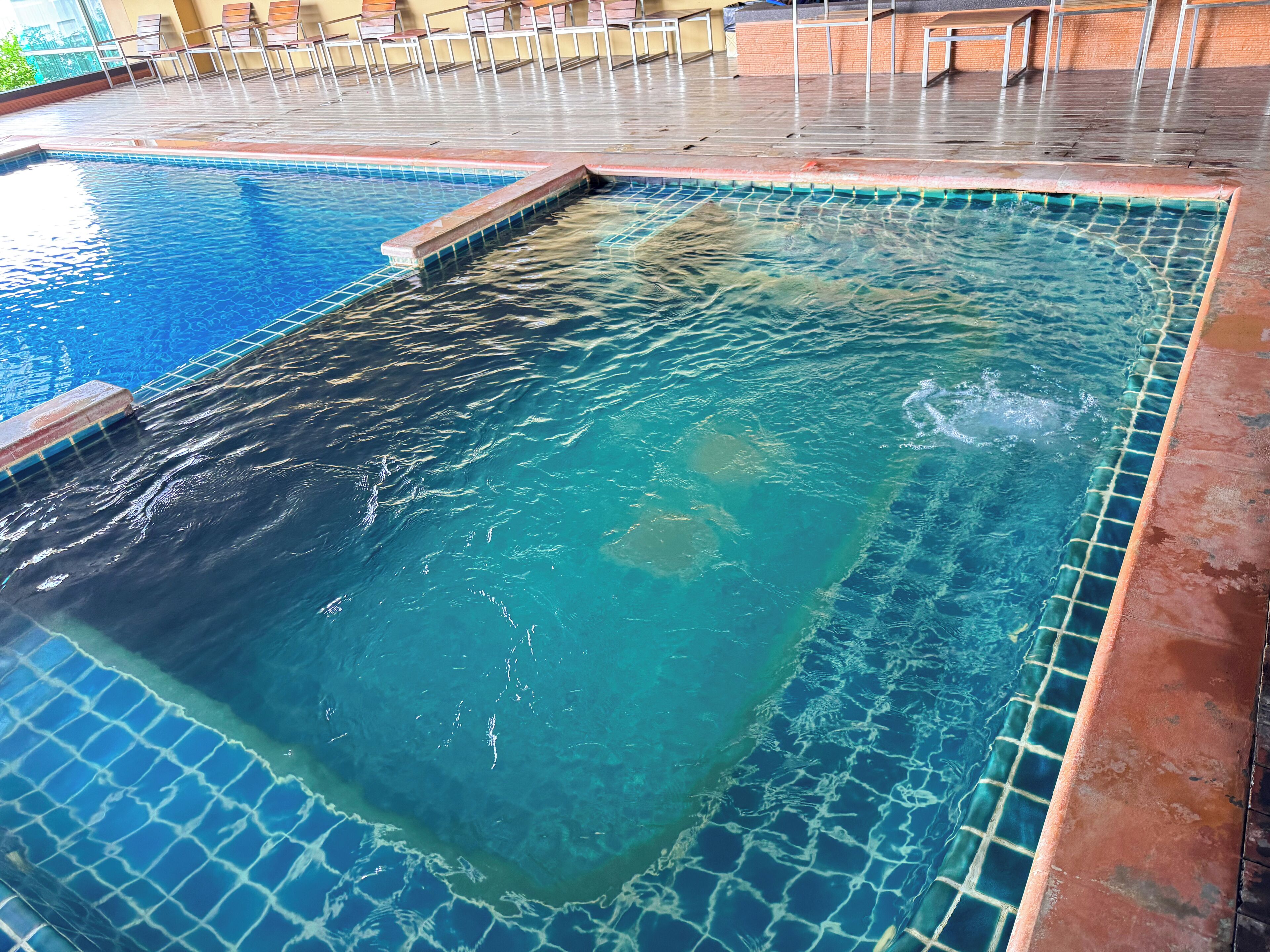 A swimming pool with clear blue water and a tiled edge.