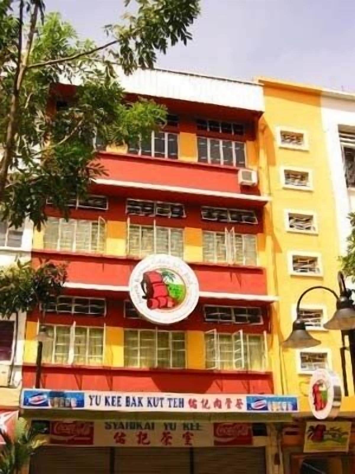A multi-story building with a red and yellow facade, featuring a circular logo with a green and red design.