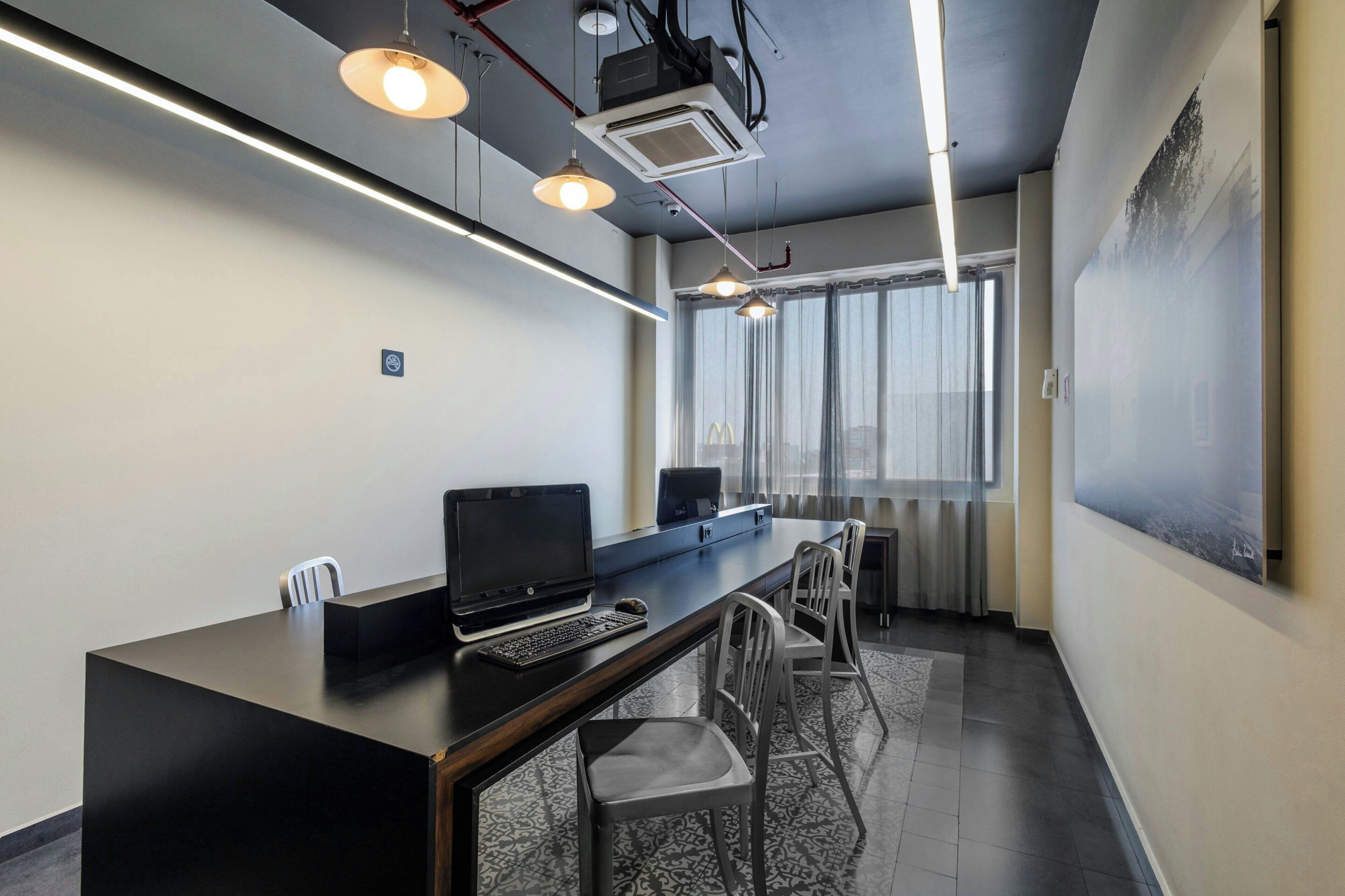 A modern office space with a long table, chairs, a laptop, and a projector.