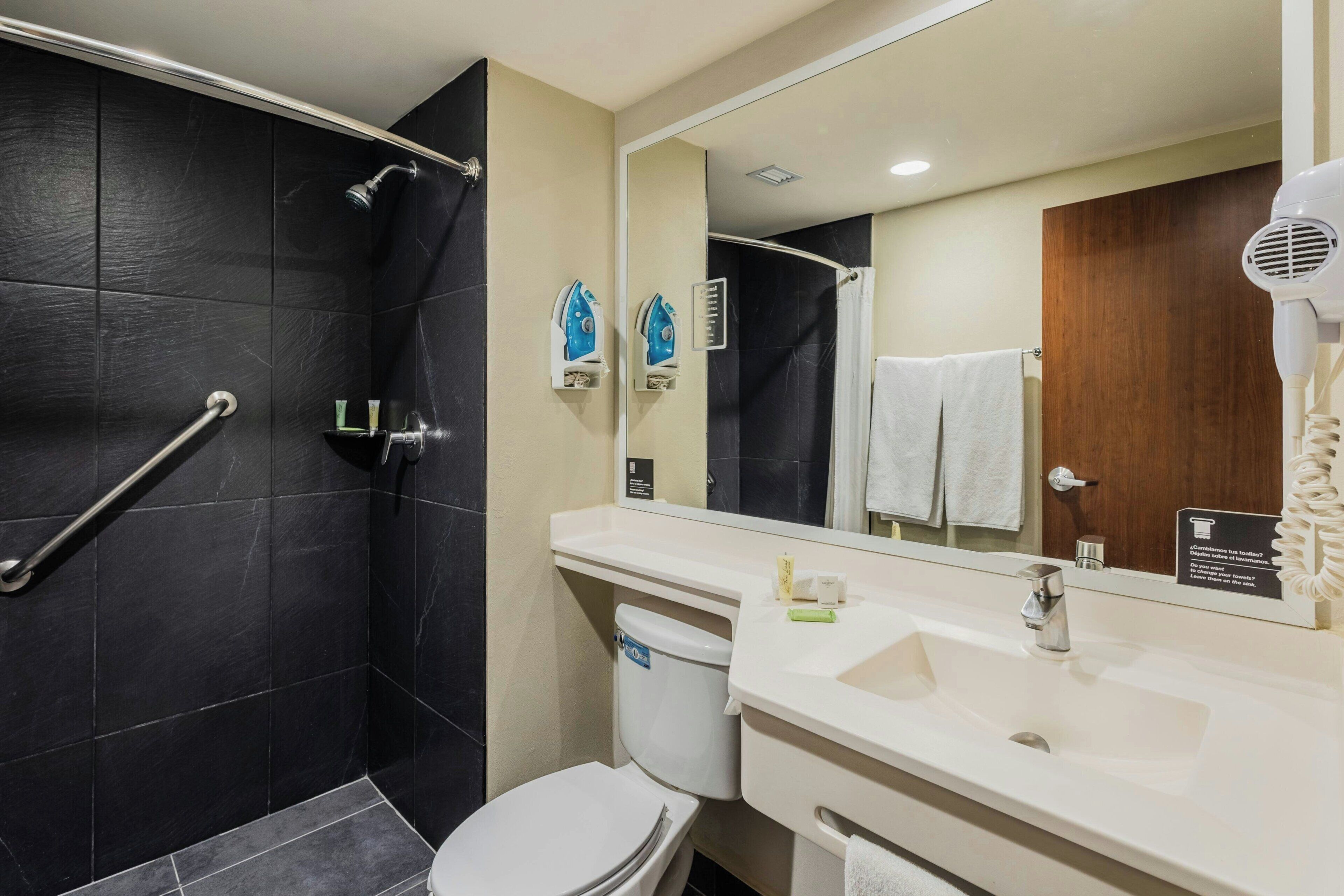 Une salle de bain moderne équipée d’une douche, de toilettes, d’un lavabo et d’un grand miroir.