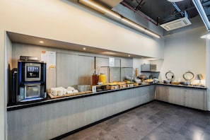 Un espace cuisine moderne comprenant une machine à café, un bar pour prendre le petit-déjeuner et divers produits alimentaires.