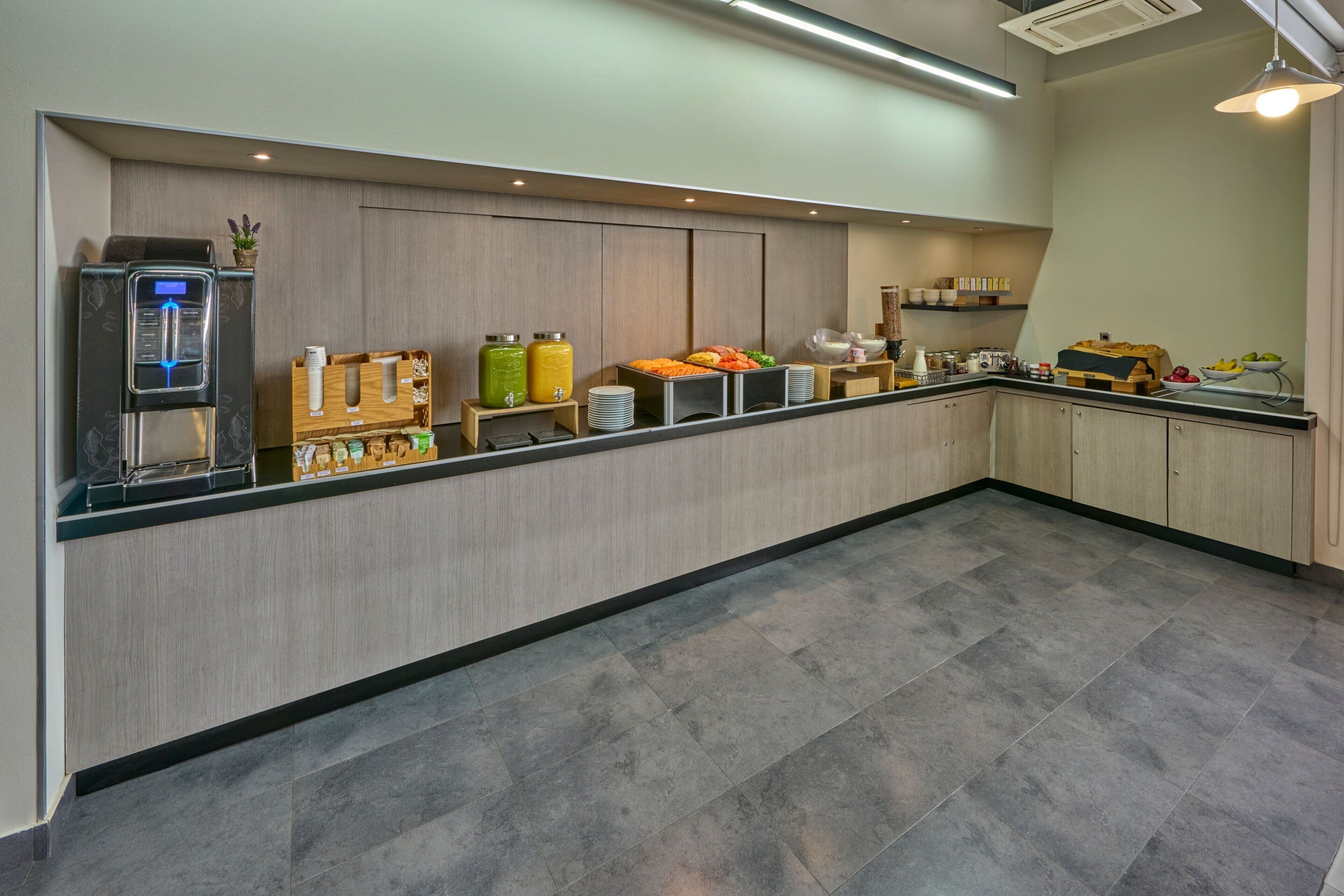 A modern kitchen with a built-in water dispenser, a coffee machine, and various food items on shelves.