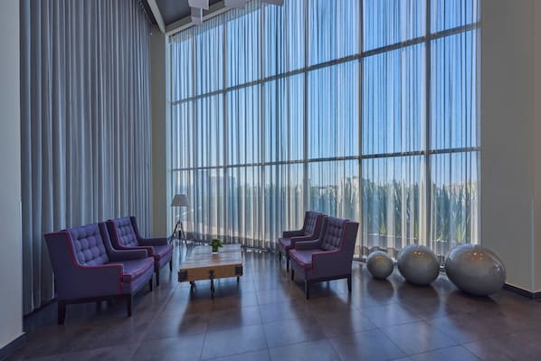 A spacious lobby with large windows, two sofas, a coffee table, and decorative spherical objects.