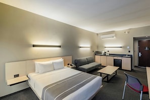 Une chambre d’hôtel comprenant un lit, un canapé, un bureau, une chaise et une kitchenette.