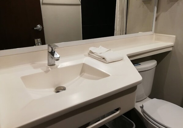 A bathroom with a white sink, a mirror, and a toilet.