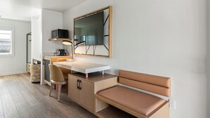 A modern, minimalist room with a wooden desk, a cushioned bench, and a large mirror. -  GoodSpring Motel (Napa)