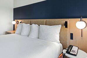 A hotel room with a large bed, bedside lamps, a bedside phone, and a wooden headboard.