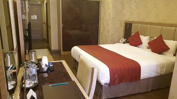 A hotel room with a bed, a desk with a laptop, a telephone, and a mirror.