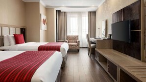 A hotel room with two beds, a desk, a chair, a TV, and a window with curtains. - Ramada by Wyndham Bishkek Centre (Bishkek)