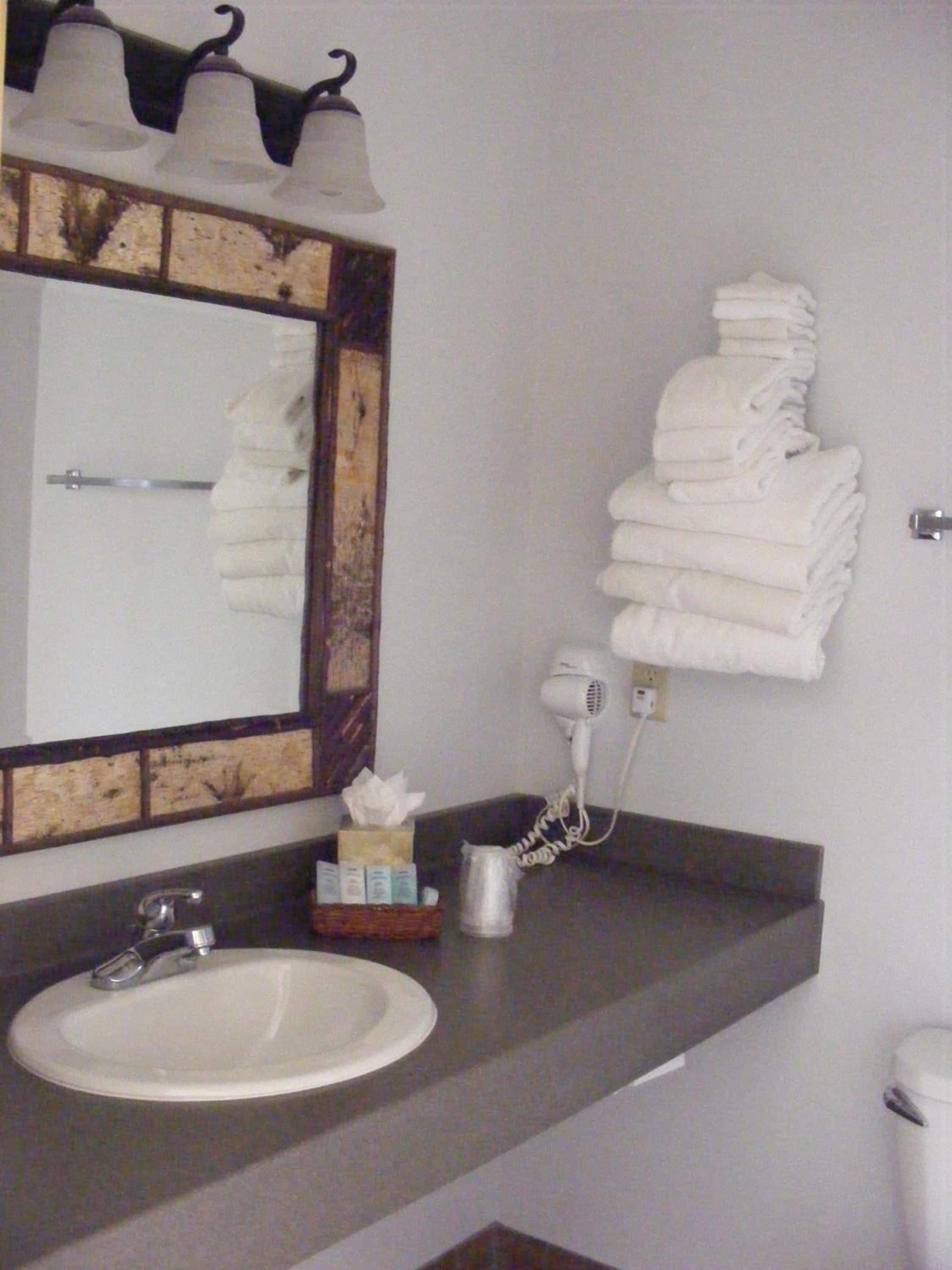 A bathroom with a sink, a mirror, a towel rack, and a hairdryer.