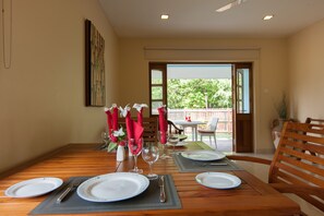 A dining table set for four with plates, cutlery, and red napkins. - Le Relax Self-Catering (La Digue)