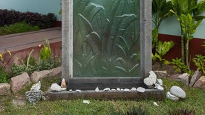Un ingresso di un edificio con un pannello di vetro decorativo, un tetto verde e piante circostanti.