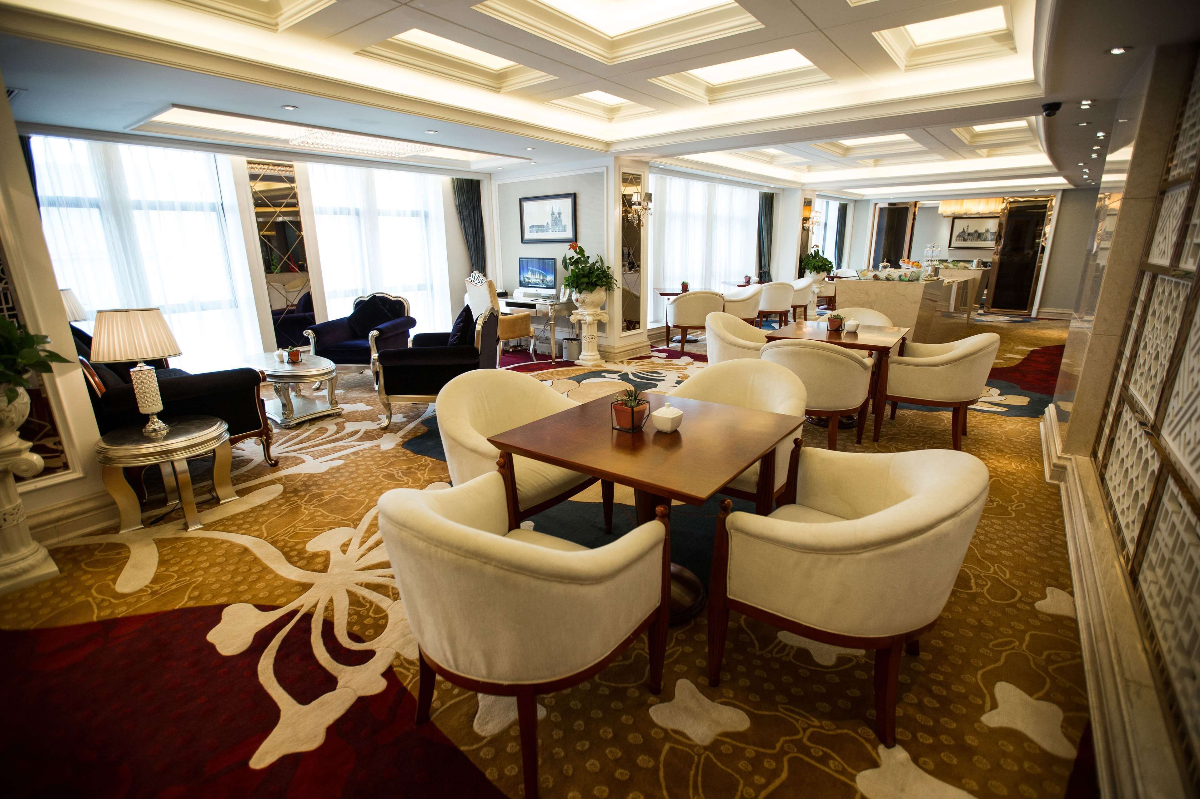 Een ruime eetzaal van een hotel met een grote tafel, meerdere stoelen en een vloerbedekking.