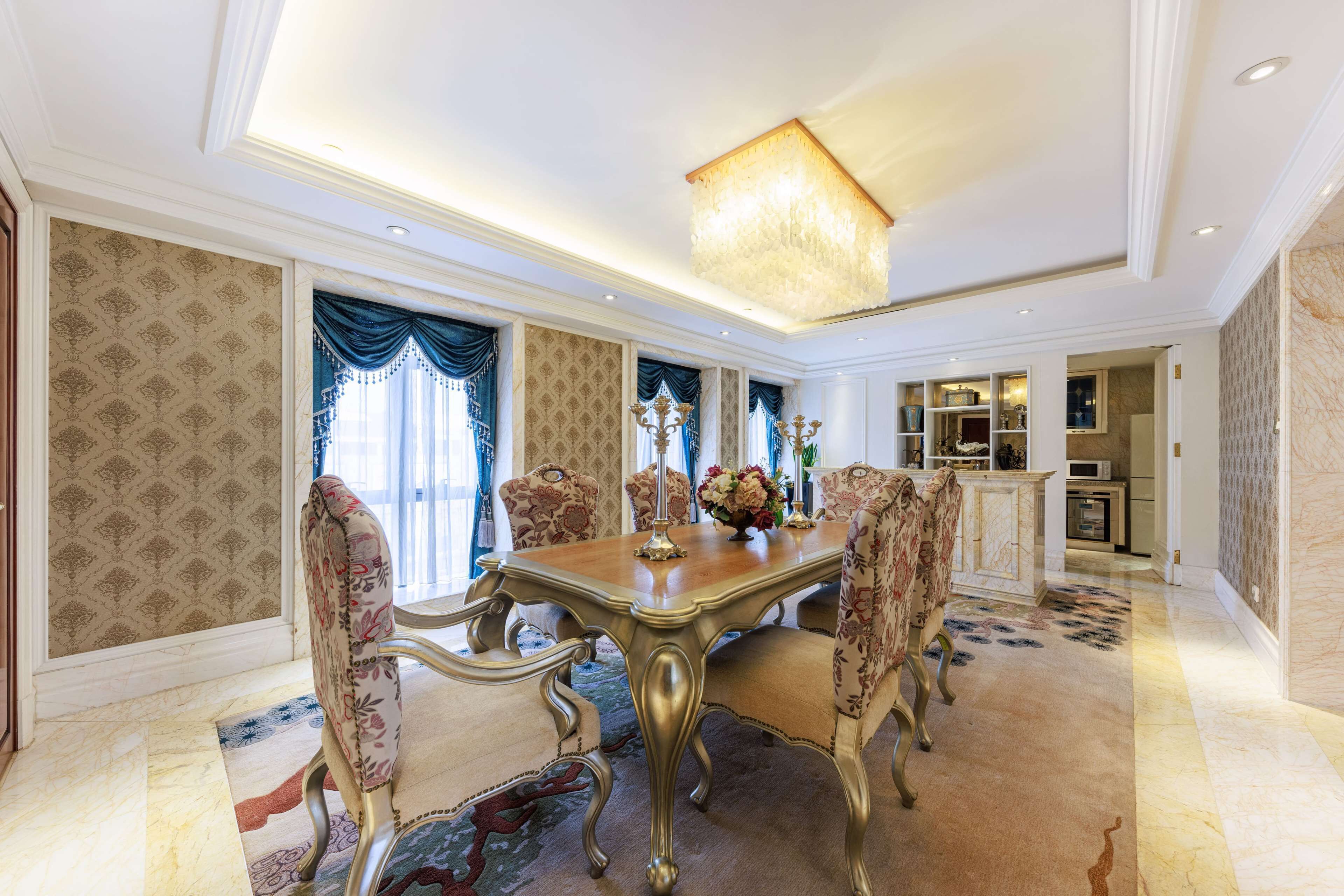 Un comedor con una mesa grande, sillas ornamentadas y una araña.