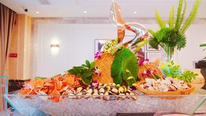Une table de buffet avec des fruits de mer, une plante décorative et un vase en verre.