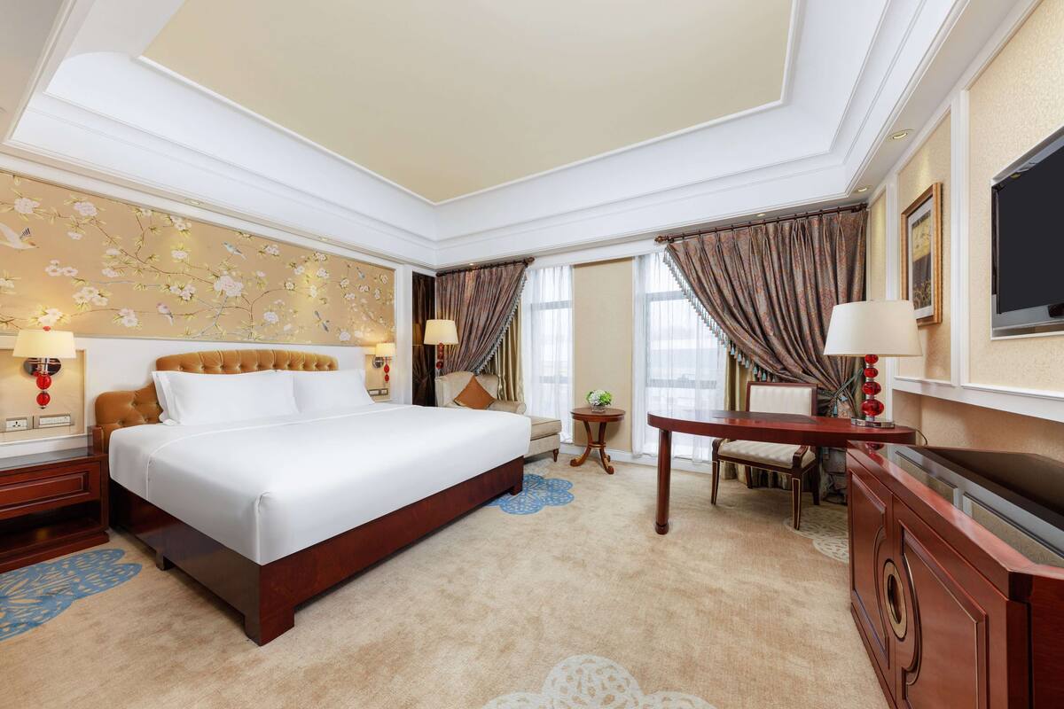 A spacious hotel room with a large bed, a desk, and a television.
