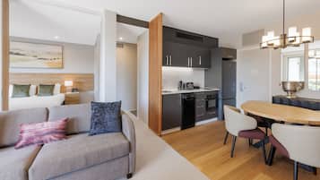Una sala de estar moderna con un sofá, una mesa de comedor con sillas y una cocina con armarios y electrodomésticos.