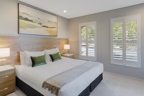 A bedroom with a large bed, two bedside tables with lamps, a headboard, and a window with shutters. - Peppers Hunter Valley Accor Vacation Club Apartments (Pokolbin)