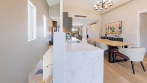 Cozinha moderna com ilha de mármore, mesa de jantar de madeira e cadeiras.