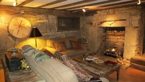 A cozy room with a stone fireplace, a sofa, a coffee table, and a clock on the wall. - The York House Inn (Rabun Gap)